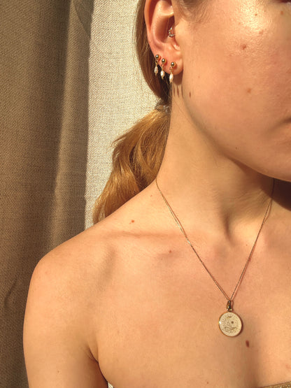 Eine Frau trägt Luna Aurea Anhaenger mit Mond Symbol auf der Haut im natürlichen Licht