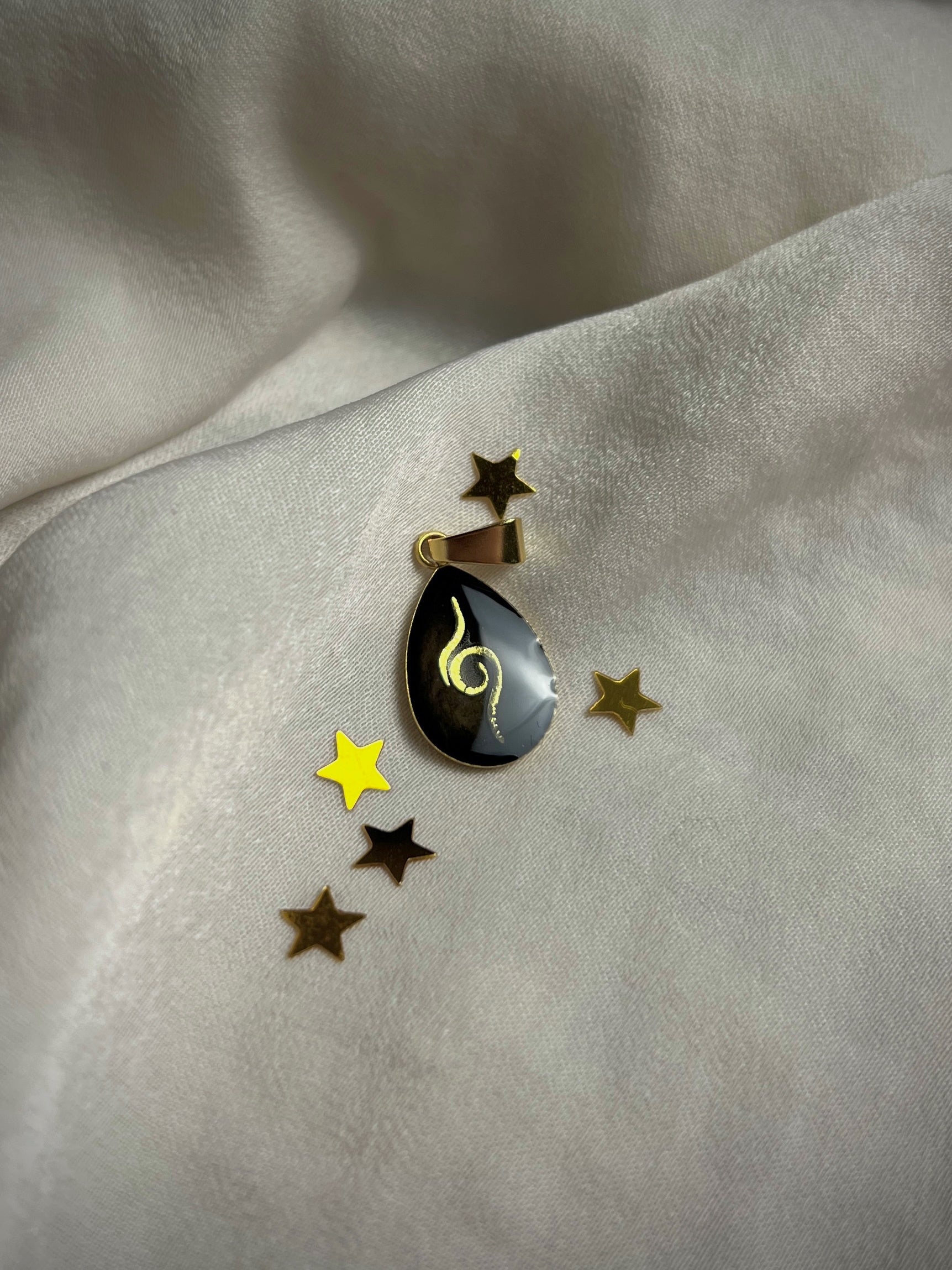 Vergoldeter Edelstahl Anhänger mit einem schwarzen Hintergrund, in Tropfenform und einer goldenen Zwillingsflamme als Symbol 